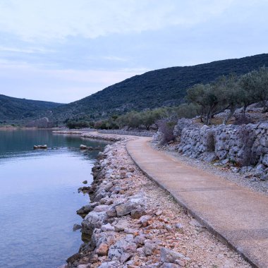 İlkbaharda gün batımından sonra Cres (Hırvatistan) yakınlarında yol ve sakin deniz