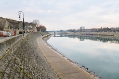 Arles, Fransa - 07 Mart 2023: Arles 'te Rhone Nehri, bulutlu bir kış akşamı, taş duvar