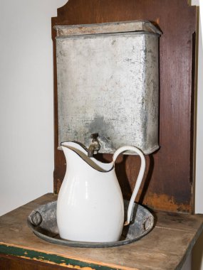 Tahta bir masanın üzerinde duran eski bir antika beyaz metal sürahi.