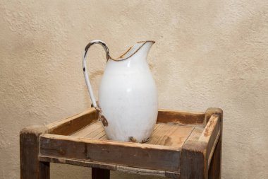 Tahta bir masanın üzerinde duran eski bir antika beyaz metal sürahi.