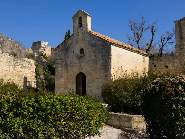 Les Baux-de-Provence, Fransa - 4 Mart 2023: Baharın güneşli bir gününde küçük bir kilise, mavi gökyüzü