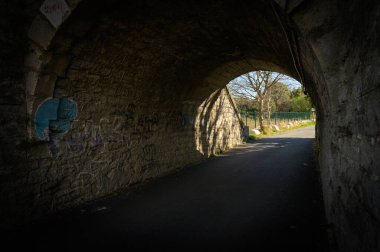 Arles, Fransa - 12 Mart 2023: Güneşli bir kış gününde eski bir demiryolu köprüsünün altındaki yol