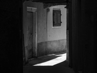 Cres, Hırvatistan - 23 Ekim 2022: Cres 'te dar bir sokak, güneş ışığı ve gölge, siyah ve beyaz