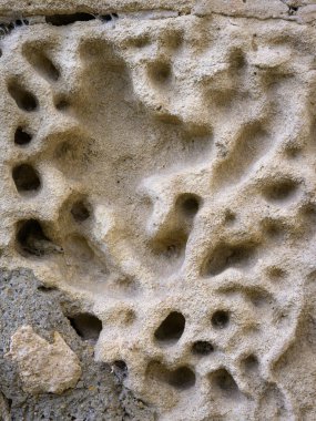 İlkbaharda bulutlu bir günde delikleri olan yıpranmış bir kayanın soyut yakın çekimi.