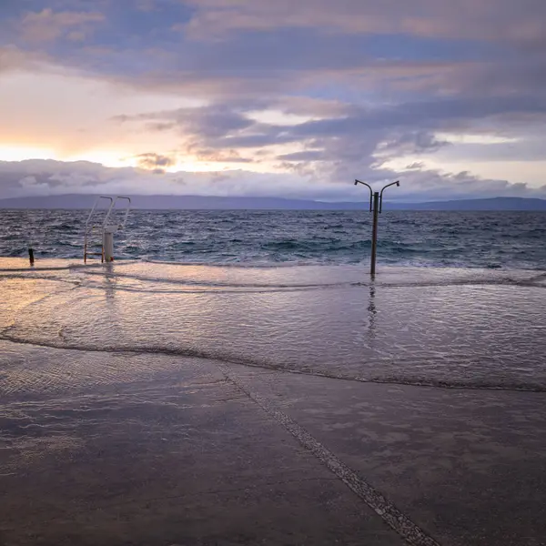 stock image Sunset with colorful clouds over the sea in Cres, high tide and flooded pavement, springtime