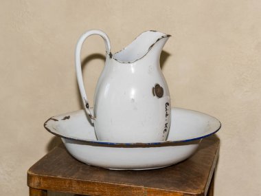 Tahta bir masanın üzerinde duran eski bir antika beyaz metal sürahi.