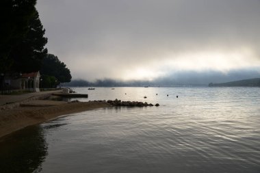 Cres, Hırvatistan - 1 Kasım 2022: Sonbaharda bulutlu ve sisli bir günde Cres yakınlarında sakin deniz