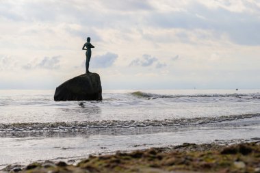 Satış, Almanya - 1 Temmuz 2024: Bulutlu bir günde bir kayanın üzerinde duran bir kızın heykeli