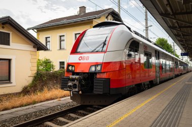 Viyana, Avusturya - 23 Mayıs 2020: İlkbaharda bulutlu bir günde kırmızı tren istasyonda duruyor