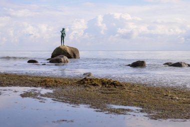 Satış, Almanya - 1 Temmuz 2024: Bulutlu bir günde bir kayanın üzerinde duran bir kızın heykeli