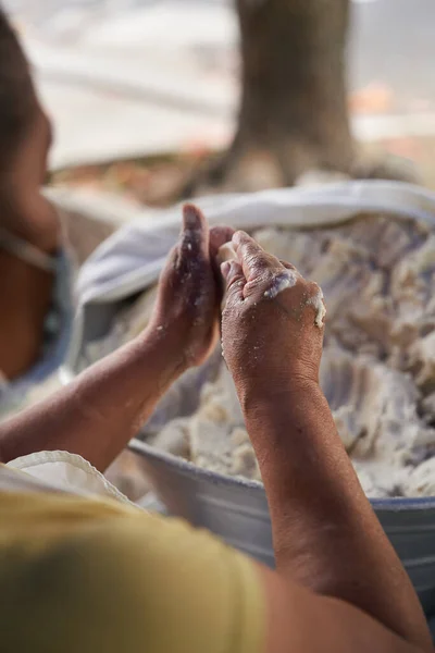 Tanınmayacak kadar yaşlı bir kadın, mütevazı mutfağındaki ızgaranın üstünde elle mısır tortillası hazırlıyor.