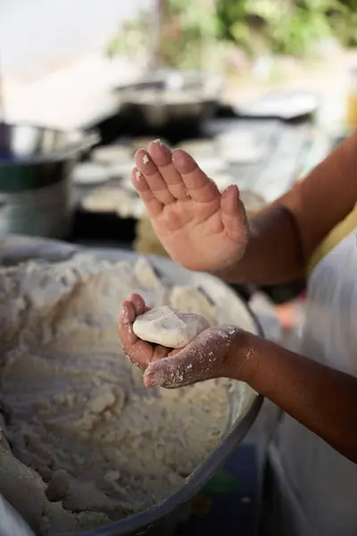 Tanınmayacak kadar yaşlı bir kadın, mütevazı mutfağındaki ızgaranın üstünde elle mısır tortillası hazırlıyor.
