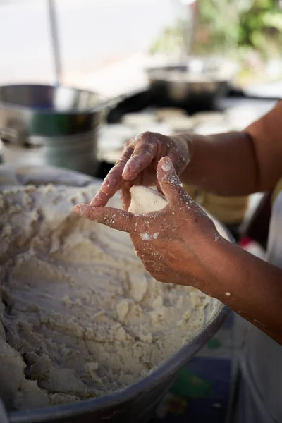 Tanınmayacak kadar yaşlı bir kadın, mütevazı mutfağındaki ızgaranın üstünde elle mısır tortillası hazırlıyor.