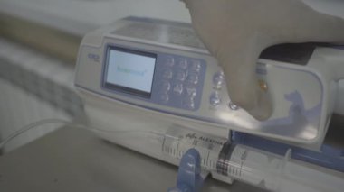 Şırınga pompası. Yakın plan çekim. Bir profesyonel şırıngayı çalıştırır. Modern tıbbi ekipmanlar. Modern veteriner ekipmanları. Yakın çekim.