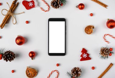 Noel süsleriyle dolu boş ekranlı akıllı telefon. Kopyalama alanı olan üst görünüm, düz yatay.