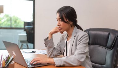 Beautiful Asian Manager attractive mature businesswoman working on laptop in her workstation.