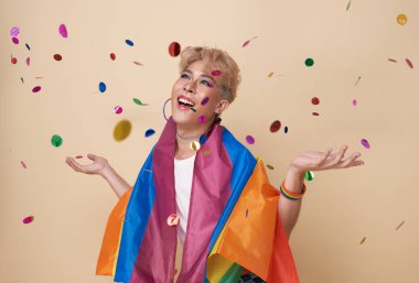 Gençlik Asyalı transseksüel LGBT çıplak renk arkaplanı üzerine izole edilmiş Gökkuşağı bayrağı ile kutlama ve konfeti yapıyor. Gay gurur bayrağı konsepti olan bir adam.