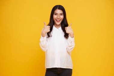 Supportive cute friendly asian girl give thumbs up and smiling, cheering for you, congratulate nice work, approving good idea, grinning glad accept plan, stand yellow background