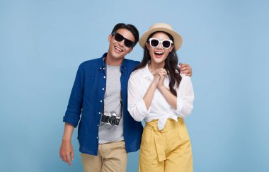 Excited Asian couple tourist dressed in summer clothes to travel on holidays isolated on blue background.