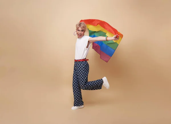 ヌードカラーの背景に隔離された虹の旗を示す若いアジア系トランスジェンダーLgbt ジェンダーの表現の誇りと平等の概念 — ストック写真