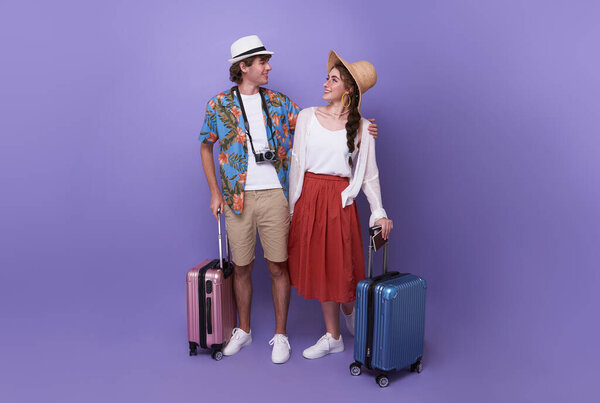 Happy couple tourist hugging together with baggage going to travel on holidays isolated on studio background.