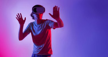 İnanılmaz teknoloji, eğlence, çevrimiçi oyun, çalışma ve sanal dünya 3 boyutlu simülasyon. VR gözlüklü ciddi bir adam oynar ve bir şeye dokunmaya çalışır, neon, stüdyo çekimi, serbest alan