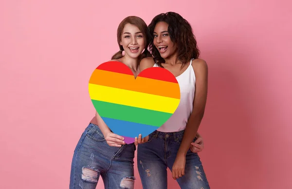 ピンクのスタジオを背景に虹色のハートLgbtqの誇りを持つ女性の陽気な笑顔の多様性グループ 同性愛嫌悪と多様性に関するレズビアンの概念Lgbtコミュニティの支援者 — ストック写真