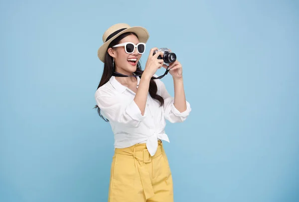 戴着夏帽的年轻亚洲女游客笑得很开心 她站在那里 相机在蓝色的摄影棚背景下拍照 — 图库照片