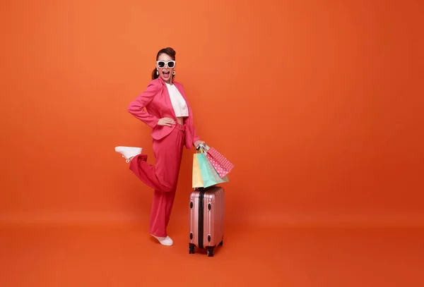 幸せな笑顔の女性の完全な長さショッピングバッグやスーツケースを運ぶ夏の販売ショッピングのためのオレンジの背景に孤立 — ストック写真