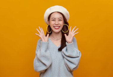 Asyalı genç kızın yüzü şaşırdı. Heyecanlı. Sarı arka planda izole edilmiş..