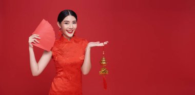 Yeni Çin yılın kutlu olsun. Kırmızı elbise giyen Asyalı kadın angpao ya da kırmızı arka planda izole edilmiş para paketi taşıyor.. 