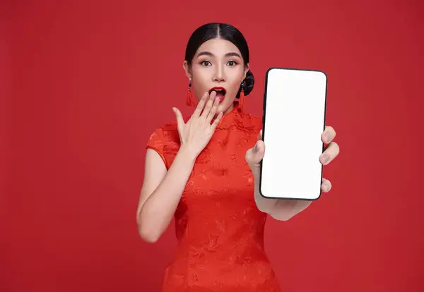 Excited Beautiful chinese Asian woman holding smartphone mockup of blank screen and smiling isolated on red background.