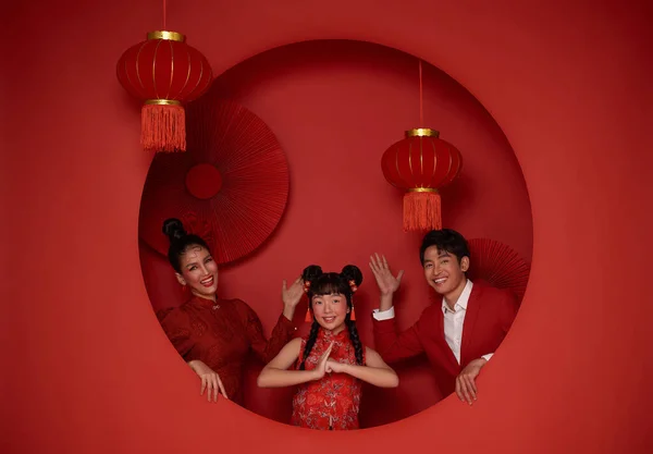 Happy asian family in red casual attire with gesture of congratulation greeting happy chinese new year 2024 on Decoration traditional red background.