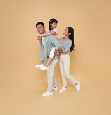 Tüm vücut portresi mutlu Asyalı aile kızına sırt üstü uzanıyor, sırt üstü uzanıyor ve çıplak bir şekilde arka planda birlikte oynuyorlar..