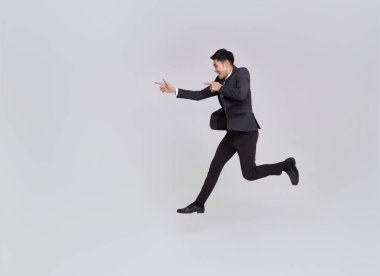 Mutlu, gülümseyen, yakışıklı Asyalı iş adamı beyaz stüdyo arka planında izole bir şekilde zıplıyor ve işaret ediyor..