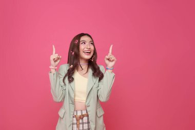 Gülümseyen Asyalı genç kız bakıyor ve yukarıdaki noktalar pembe arka planda izole edilmiş reklam metnin için yer gösteriyor.