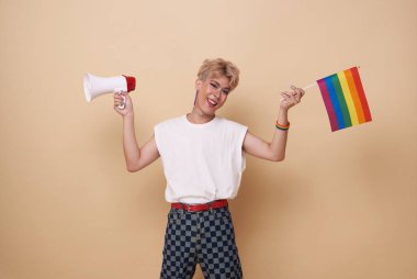 Mutlu gülümseyen Asyalı transseksüel LGBT elinde gökkuşağı bayrağı ve megafon ile çıplak arkaplanda izole edilmiş eşitliği ilan ediyor..