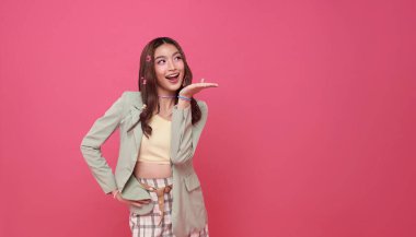 Mutlu Asyalı kadın pembe arka planda izole edilmiş ürünler için açık avuç içi fotokopi alanı sunar veya gösterir