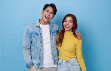 Asyalı mutlu bir çiftin mavi arka planda sarılıp gülen portresi..