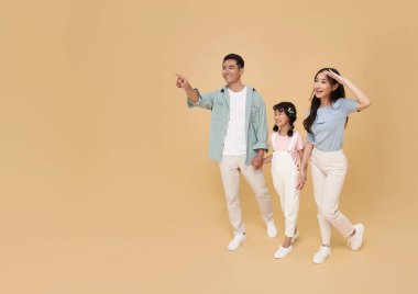 Mutlu gülümseyen Asyalı aile portresi çıplak renkli fotokopi arkaplanına parmak basıyor.