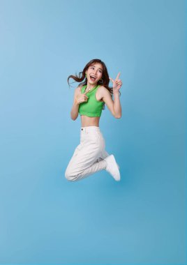 Tüm vücut uzunluğunda çılgın Asyalı kız mavi arka planda izole edilmiş iyi bir alışveriş gününü işaret ederek kutluyor.