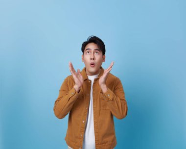 Komik Asyalı adam. Şaşırmış ve yüzü açık. Mavi arka planda tek başına..