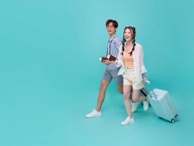 Mutlu, genç Asya 'lı turist çift, ellerinde bavullarıyla yaz tatilinde seyahate giderken mavi arka planda el ele tutuşuyorlar. Tatil tarihi kavramı