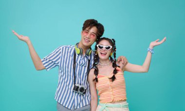 Yaz kıyafetleri içinde mutlu genç Asyalı çift. Mavi arka planda izole edilmiş yaz tatiline hoş geldiniz..