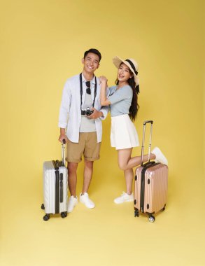 Mutlu Asyalı turist çiftin yaz yolculukları sarı arka planda izole edilmiş..