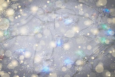 Altın kar taneleri ve renkli ışıkları olan bir çelenk ile soyut Noel arkaplanı.