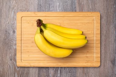 Branch of ripe bananas on a kitchen board, top view