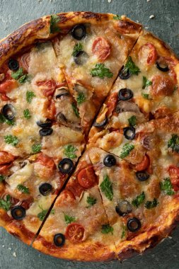 Yeşil taştan arka planda yeşillikleri olan lezzetli vejetaryen domates ve peynirli pizza.