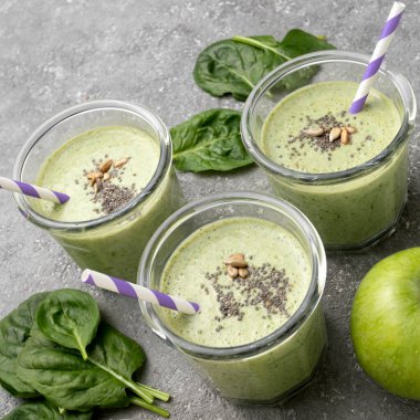 Sağlıklı yeşil ıspanak suyu cam kavanozlarda ve gri beton arka planda diğer malzemeler. Superfood, detoks, diyet, sağlıklı yiyecekler. Kereviz, elma, ıspanak, ıspanak ve muz..