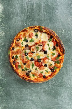 Yeşil taştan arka planda yeşillikleri olan lezzetli vejetaryen domates ve peynirli pizza.